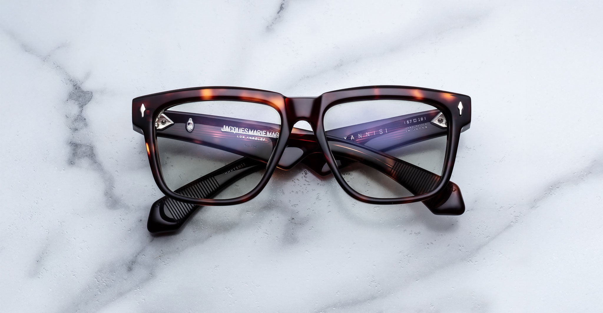Jacques Marie Mage Hyannis tortoiseshell rectangular eyeglass frames with thick edges displayed elegantly on a white marble surface.