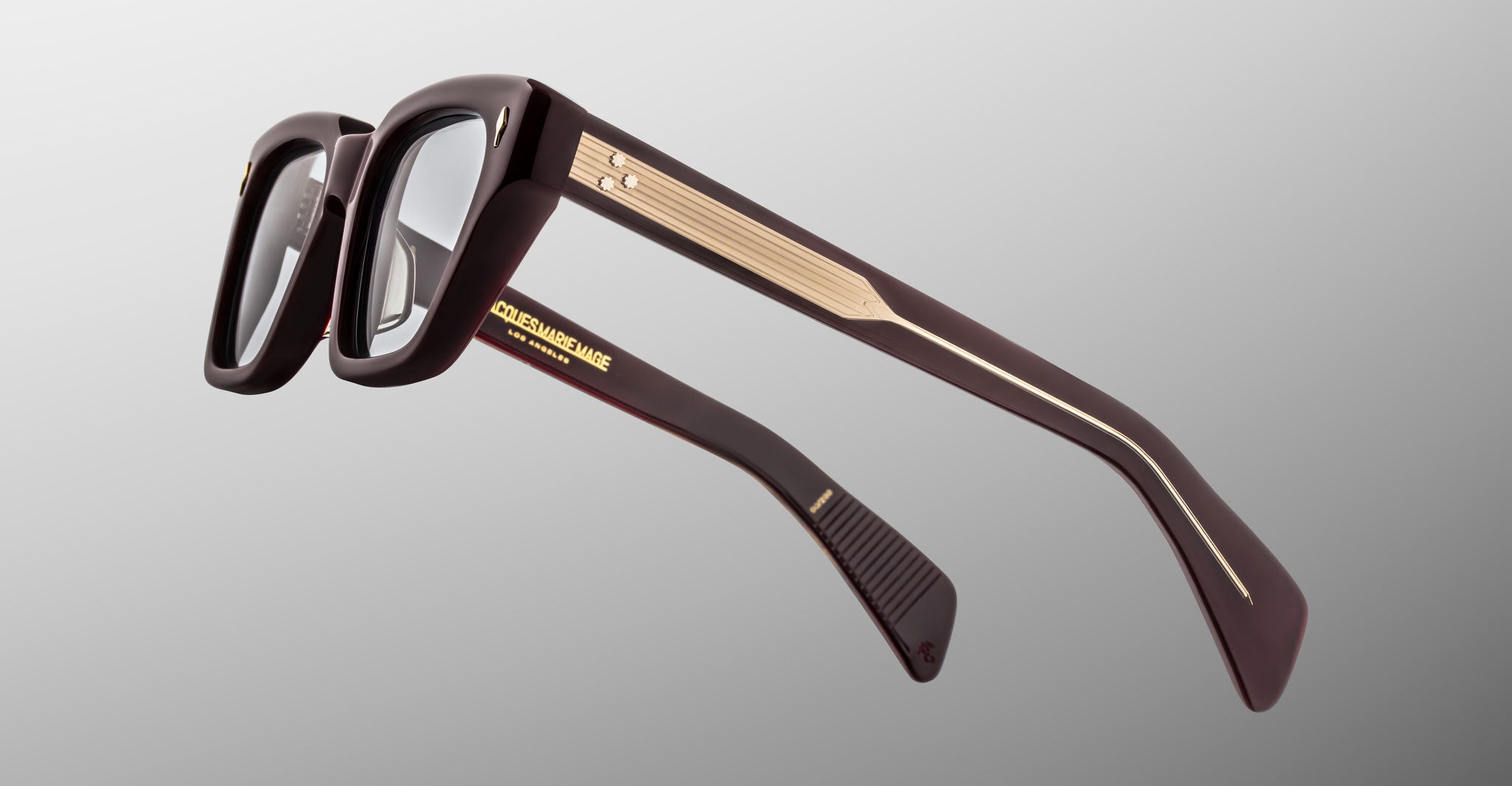 Close-up of Jacques Marie Mage Ichikawa rectangular eyeglasses, dark frame with gold accents, front view.