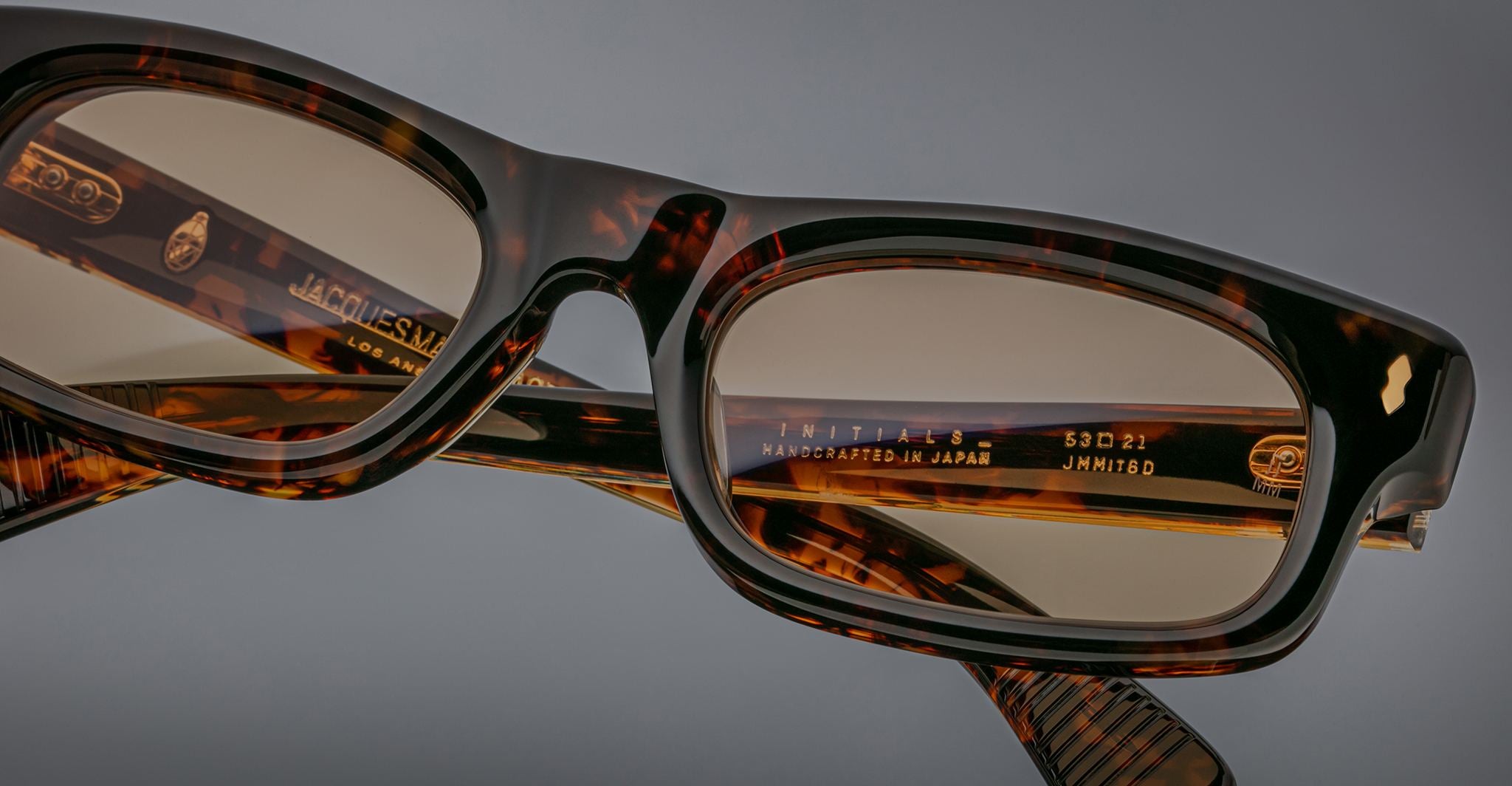 Close-up of Jacques Marie Mage Initials eyeglasses in brown tortoiseshell, highlighting frame details, hinge, and engraved size and branding—these limited-edition frames exemplify the exceptional craftsmanship of Jacques Marie Mage.