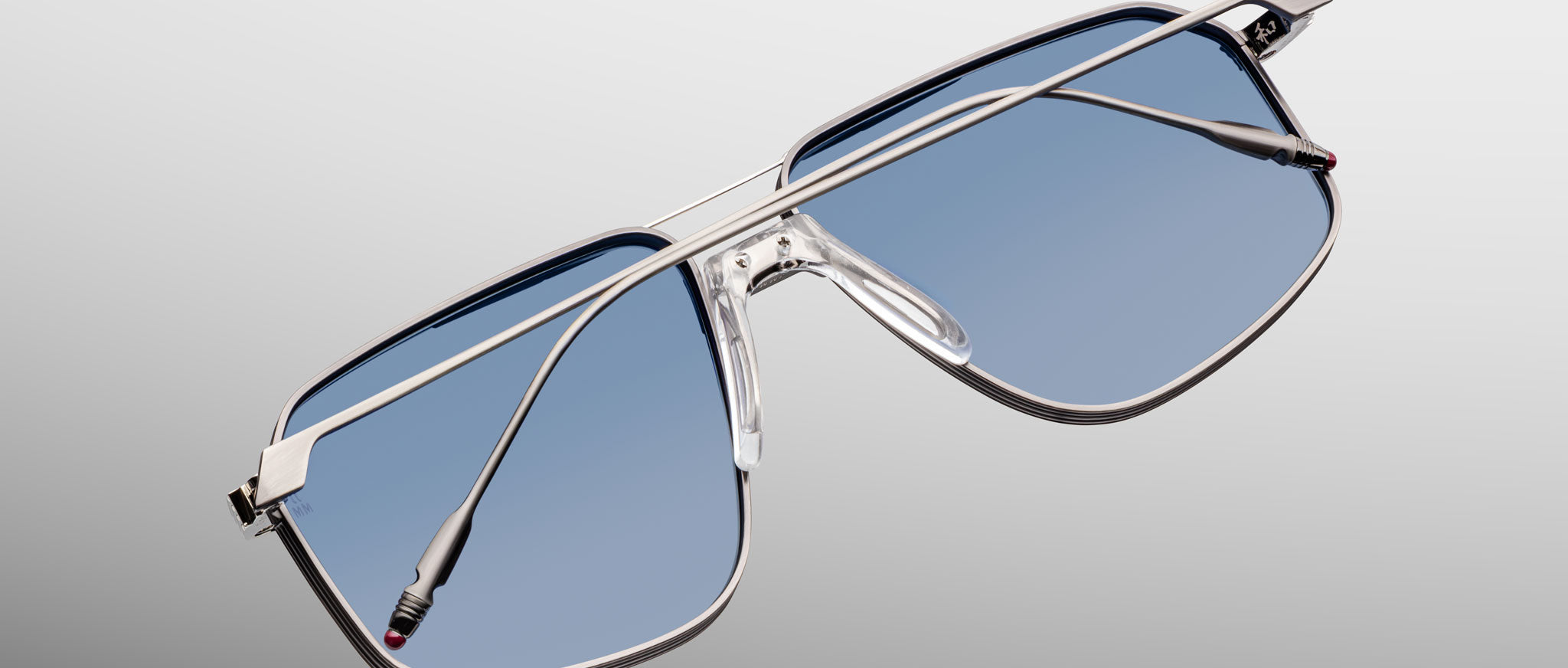 Jacques Marie Mage Jagger oversized aviator sunglasses with silver frames and blue-tinted beta titanium lenses by Jacques Marie Mage, shown against a gradient gray background.