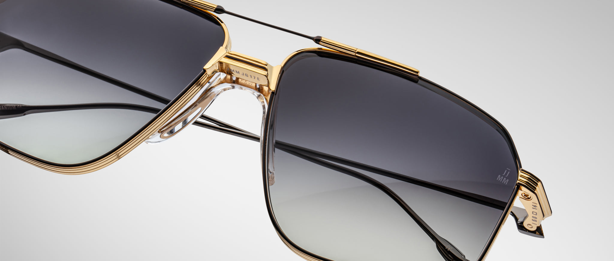 Close-up of Jacques Marie Mage Jagger sunglasses by Jacques Marie Mage, showcasing oversized aviator style with gold beta titanium frames and gradient gray lenses against a plain background.