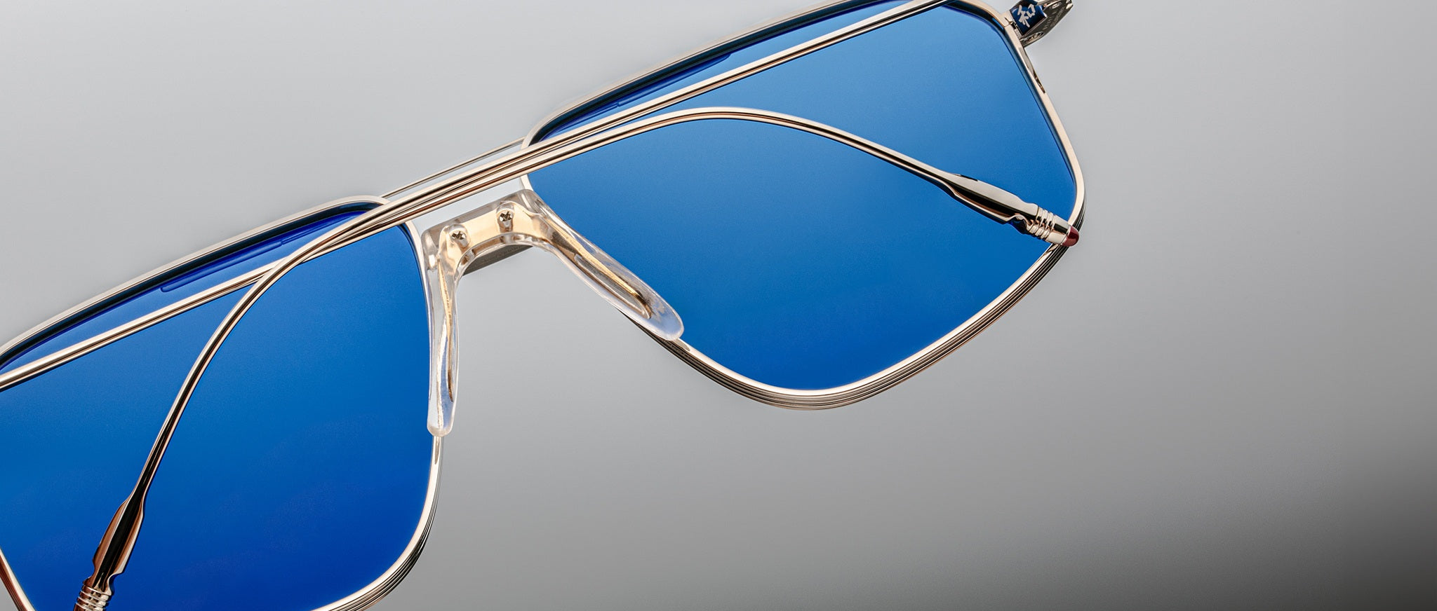 Close-up of Jacques Marie Mage Jagger sunglasses featuring oversized aviator design, blue-tinted lenses, and a sleek beta titanium metallic frame by Jacques Marie Mage, displayed on a neutral background.