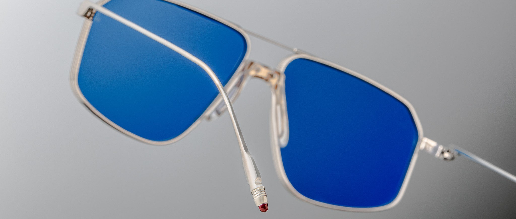 The Jacques Marie Mage Jagger sunglasses by Jacques Marie Mage feature silver oversized aviator frames with striking blue lenses, shown close-up against a neutral background.