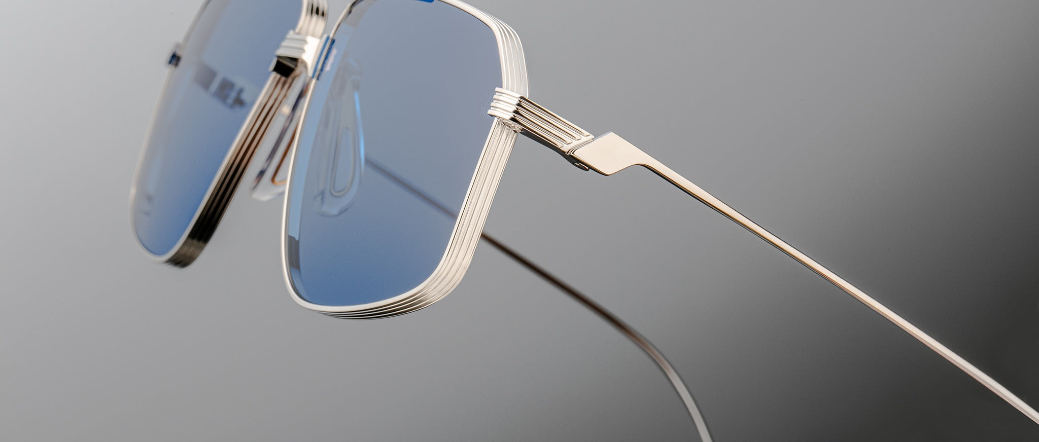 Close-up of Jacques Marie Mage Jagger oversized aviator sunglasses by Jacques Marie Mage, featuring blue-tinted lenses and sleek beta titanium frames against a neutral background.