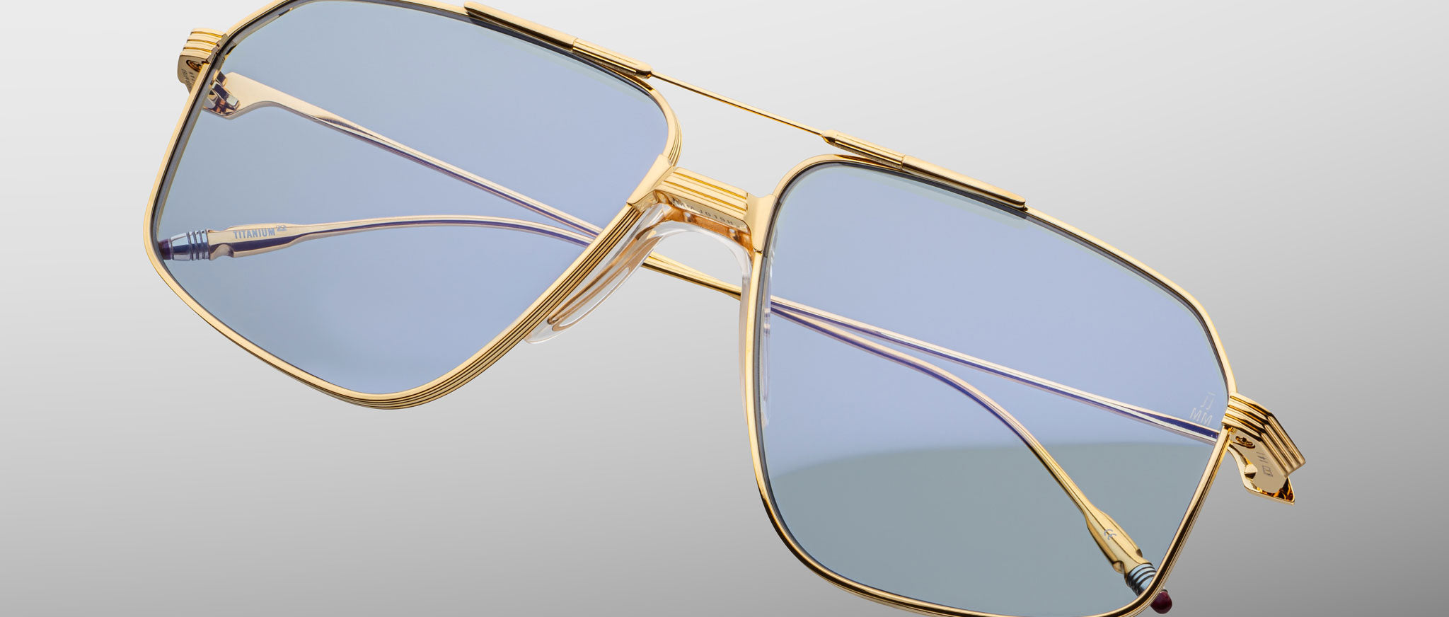 Jacques Marie Mage Jagger gold-framed oversized aviator sunglasses with blue-tinted lenses by Jacques Marie Mage, displayed on a light gray background.