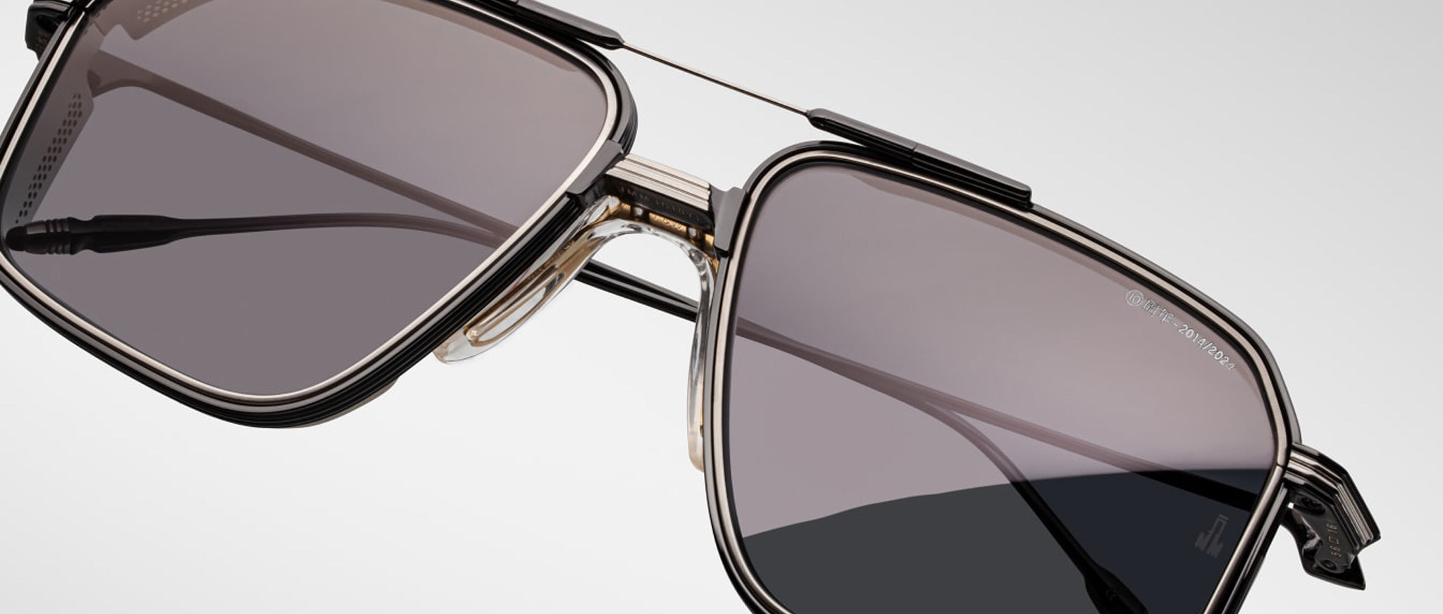 Close-up of Jacques Marie Mage Jagger sunglasses by Jacques Marie Mage, showcasing oversized square aviator frames in beta titanium with dark tinted lenses against a plain light background.