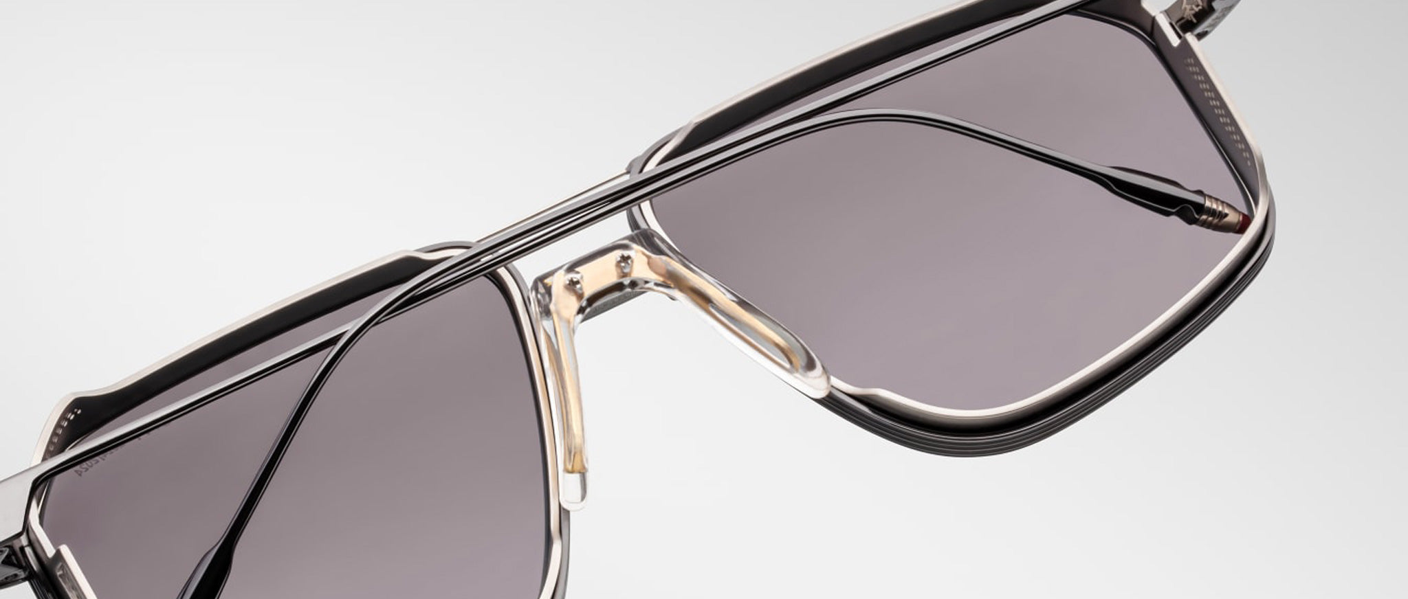 Close-up of Jacques Marie Mage Jagger sunglasses by Jacques Marie Mage, showcasing oversized aviator frames with dark tinted lenses, a double bridge, and sleek beta titanium accents set against a light background.