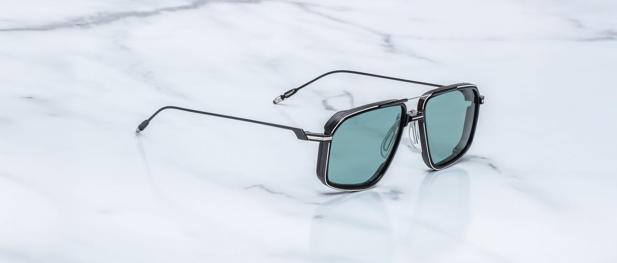 Jacques Marie Mage Jagger sunglasses with black rims and green lenses, shown from above.