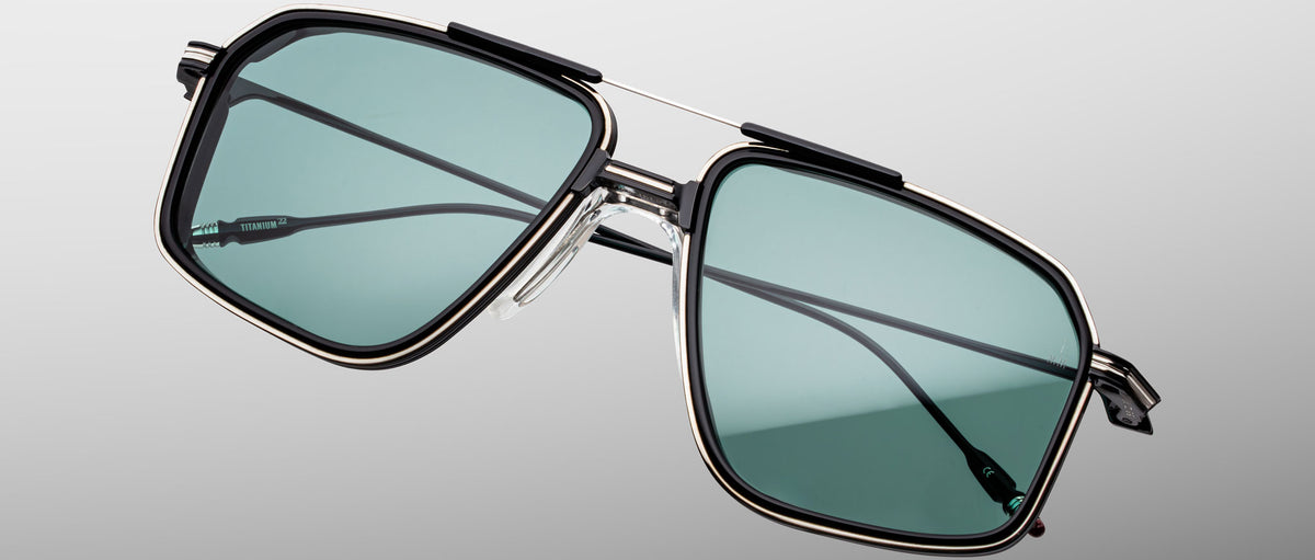 Jacques Marie Mage Jagger sunglasses, rectangular shape, teal lenses, black and silver metal frame, front view.