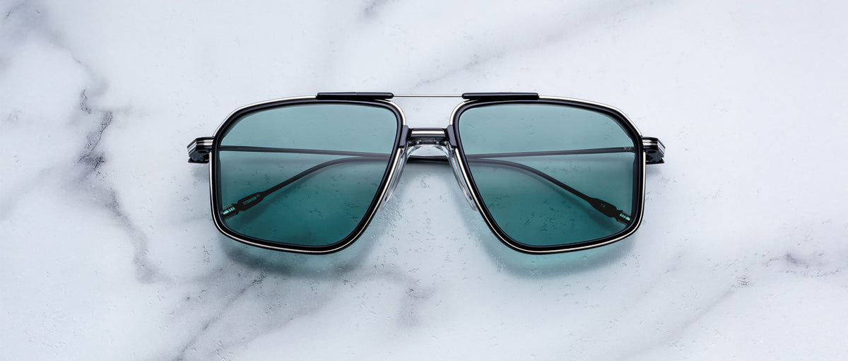 Jacques Marie Mage Jagger sunglasses feature teal lenses and a square frame, shown from above.