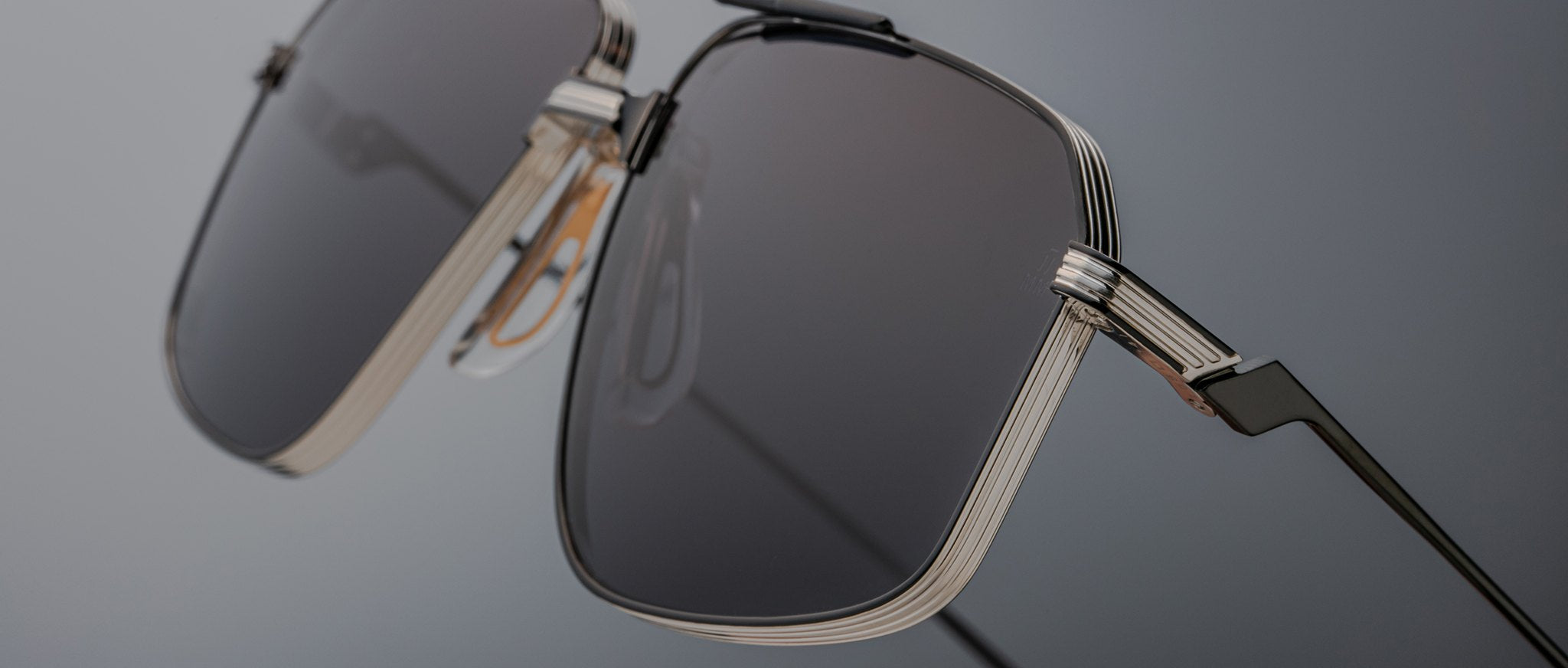 Close-up of Jacques Marie Mage Jagger sunglasses by Jacques Marie Mage, showcasing oversized aviator design with dark rectangular lenses and sleek beta titanium metallic frames against a neutral background.