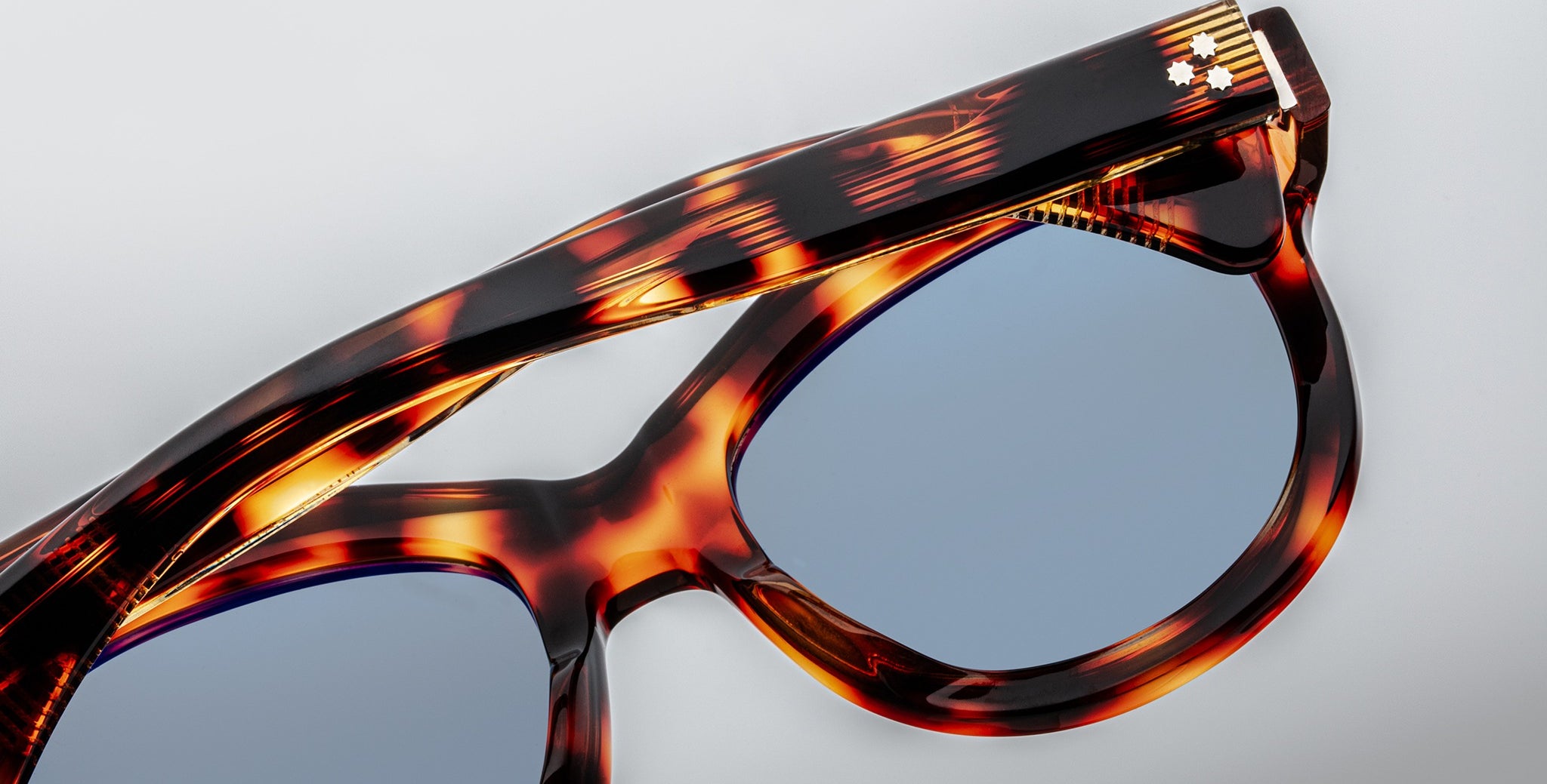 Close-up of Jacques Marie Mage Jennie sunglasses with blue lenses, detailed frame, and visible durable hinge.