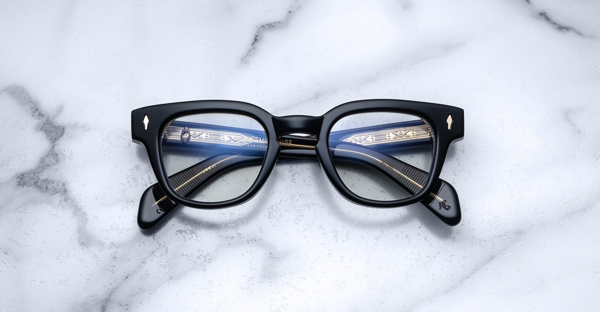 Jacques Marie Mage Julien in Beluga rectangular optical frame in deep black acetate with a smooth, polished finish, featuring a keyhole bridge, signature arrowhead front pins, and exposed metal core detailing within the temples, shown with clear lenses.