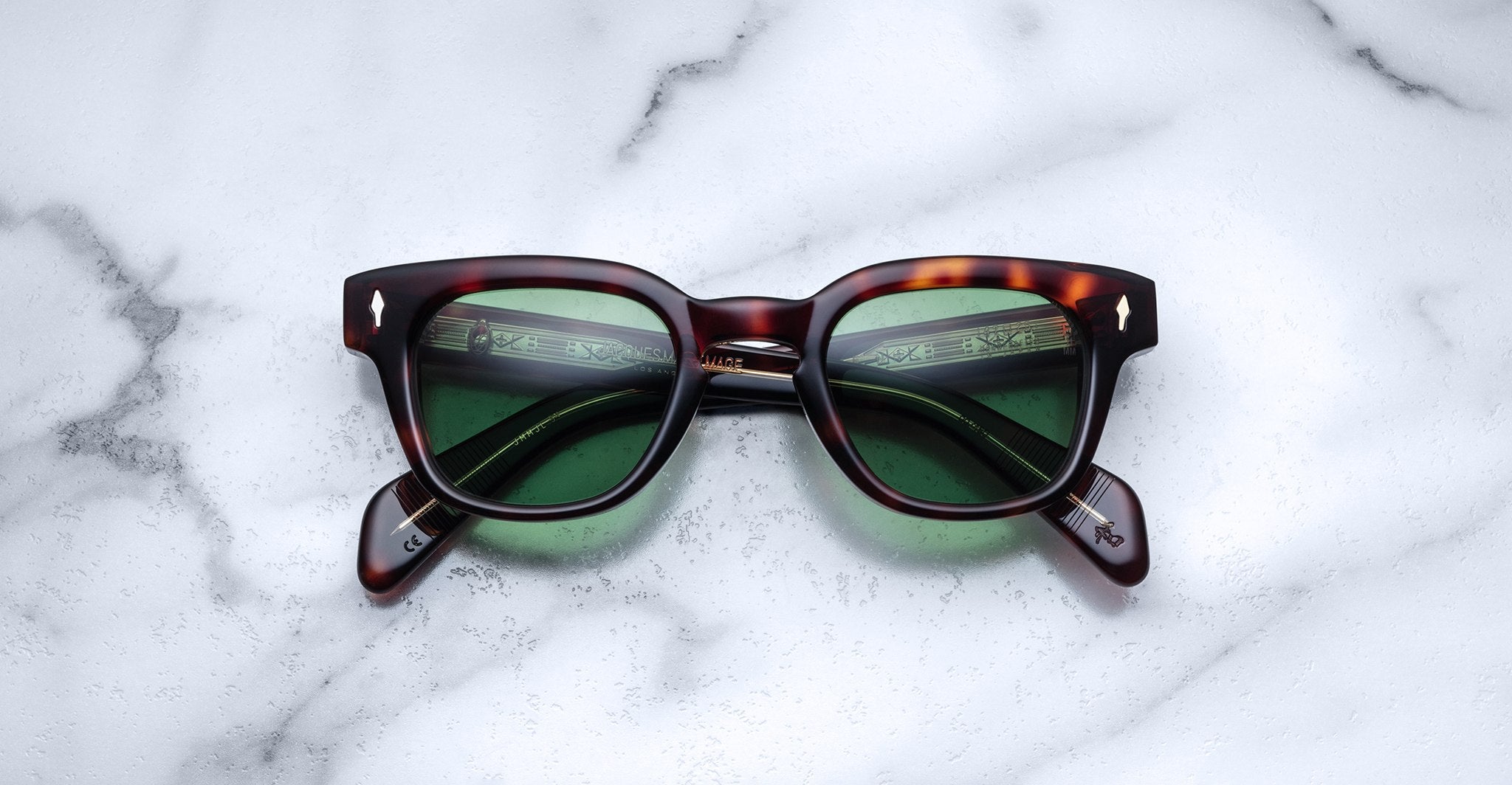 Jacques Marie Mage Julien in Havana 5 rectangular sunglass in brown tortoiseshell acetate with warm amber undertones, featuring a keyhole bridge, signature arrowhead front pins, and exposed metal core detailing within the temples, fitted with green-tinted lenses.