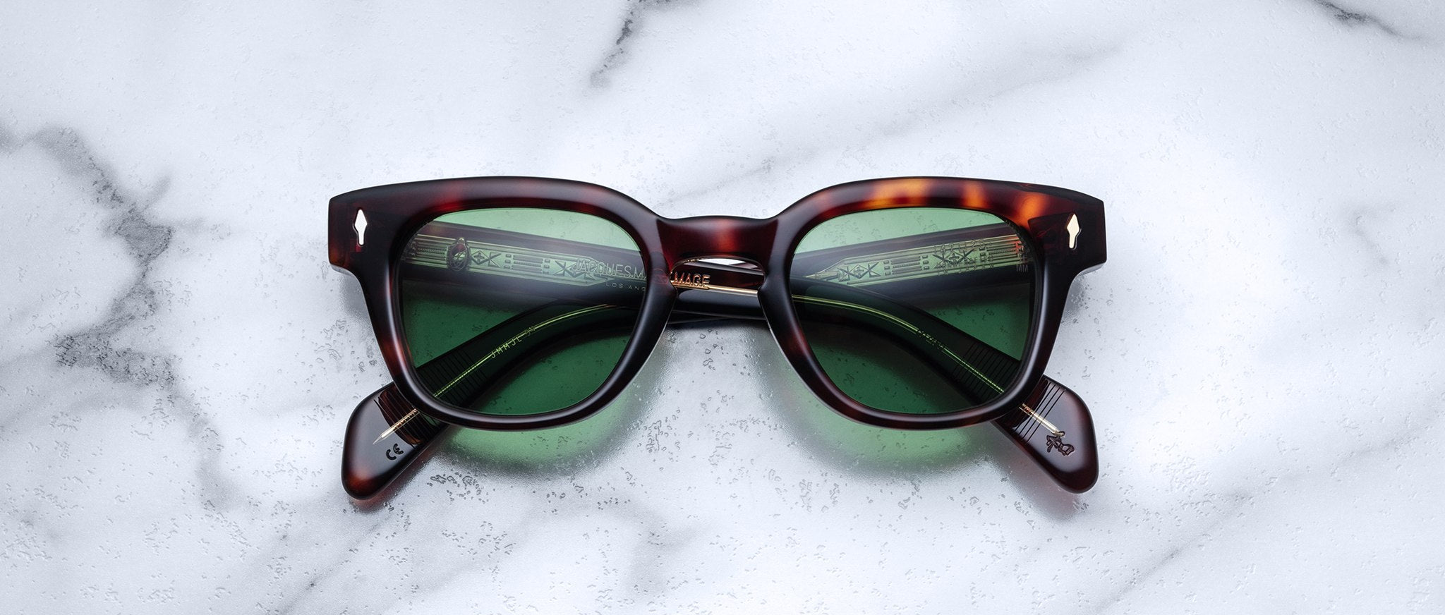 Jacques Marie Mage Julien in Havana 5 rectangular sunglass in brown tortoiseshell acetate with warm amber undertones, featuring a keyhole bridge, signature arrowhead front pins, and exposed metal core detailing within the temples, fitted with green-tinted lenses.