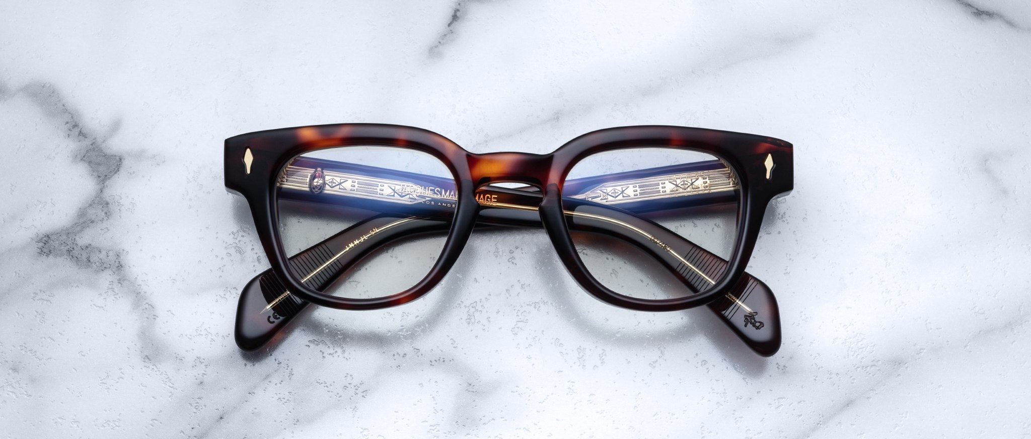Jacques Marie Mage Julien in Havana 5 rectangular optical frame in rich brown tortoiseshell acetate with subtle amber highlights, featuring a keyhole bridge, signature arrowhead front pins, and exposed metal core detailing within the temples, shown with clear lenses.