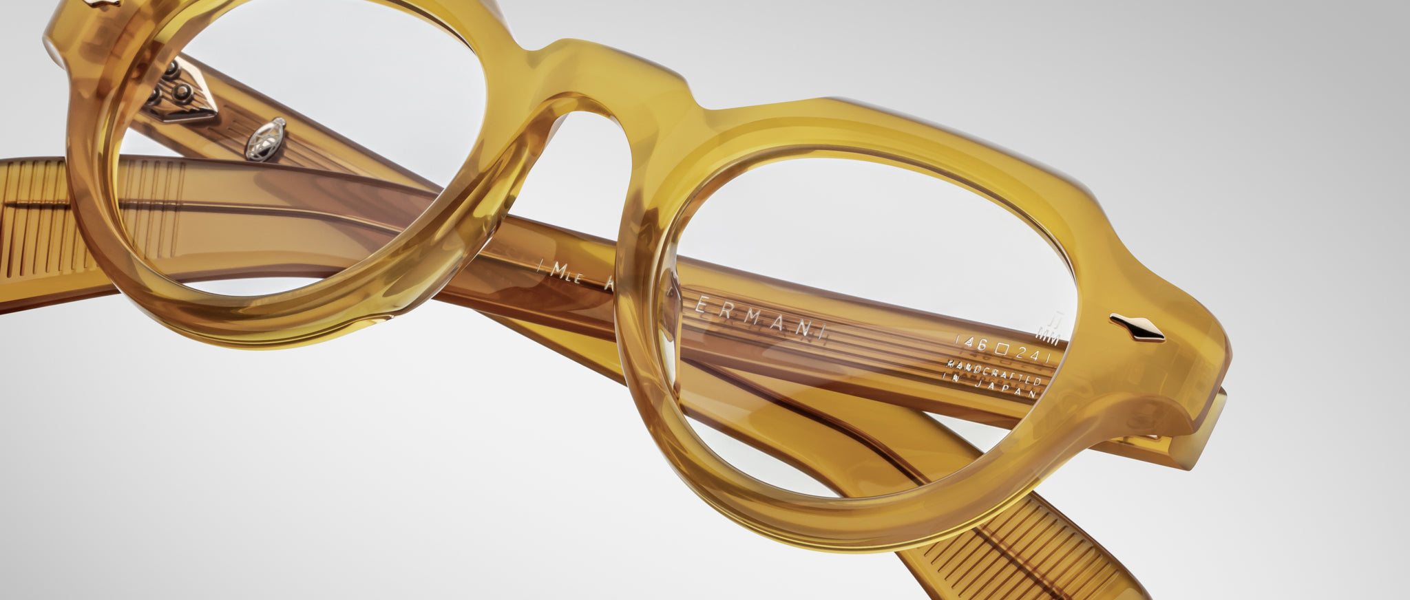 Close-up of Jacques Marie Mage Kellerman eyeglasses—round, translucent yellow frames with thick rims and folded arms—set against a light gray background.