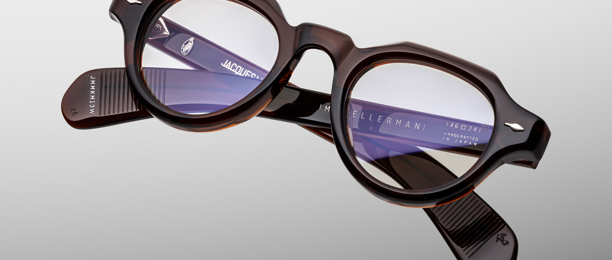 The Jacques Marie Mage Kellerman eyeglasses feature round, dark tortoiseshell thick frames with clear lenses, displayed on a light gray background. Branding and product details appear in white text on the inner arms.