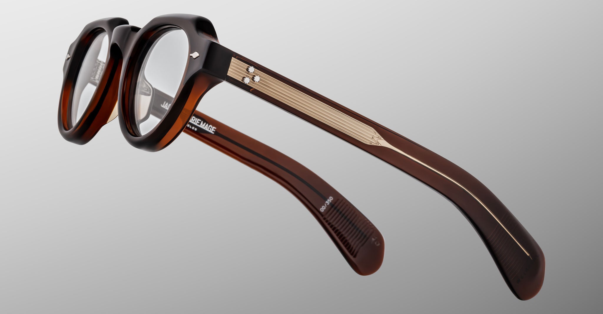 The Jacques Marie Mage Kellerman eyeglasses feature thick brown tortoiseshell frames with metal-accented arms, shown from a side and slightly overhead angle against a plain light gray background.