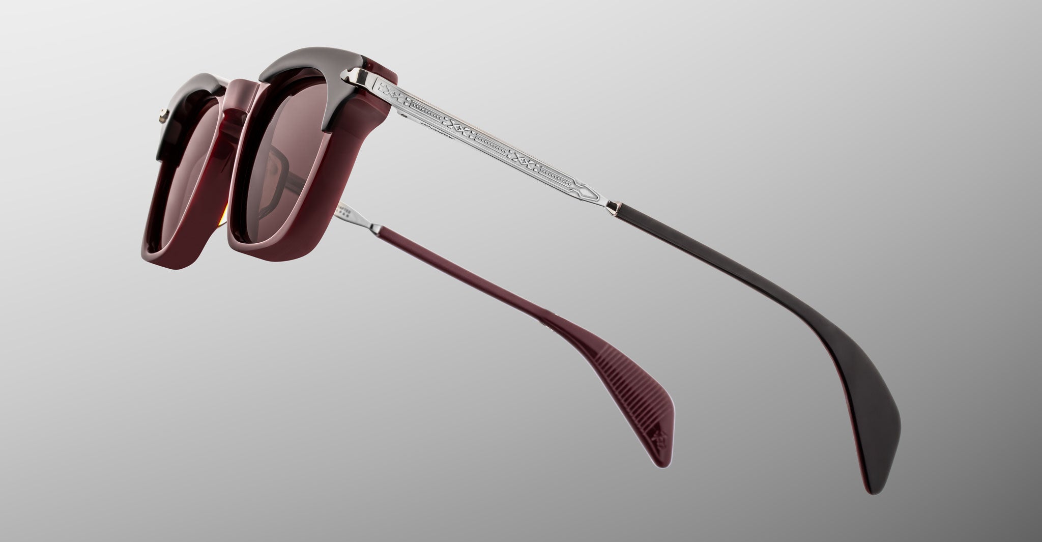 Jacques Marie Mage Kennedy sunglasses with maroon frames, metal arms, and engravings shown from the front at a straight-on angle.