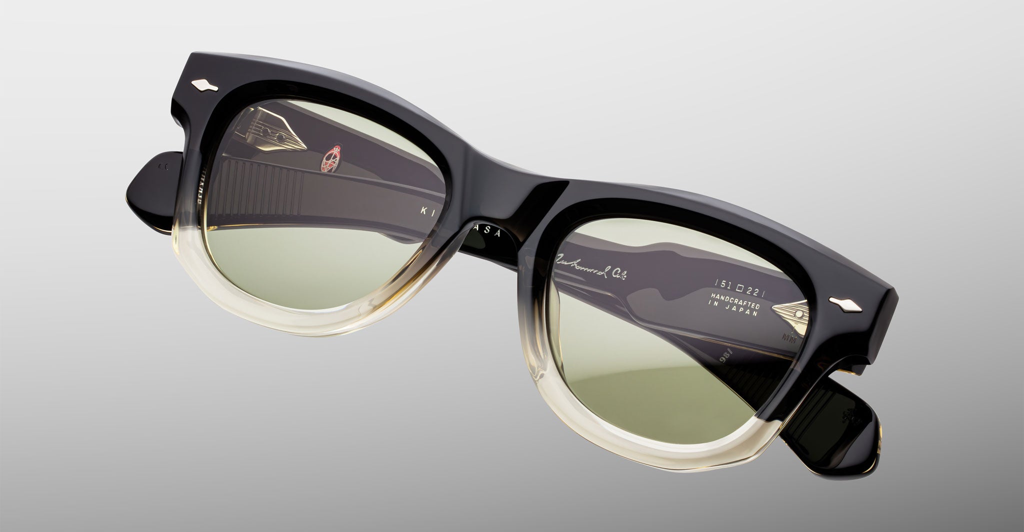 Jacques Marie Mage Kinshasa sunglasses with black and clear frames, green polarized lenses, shown from the front.