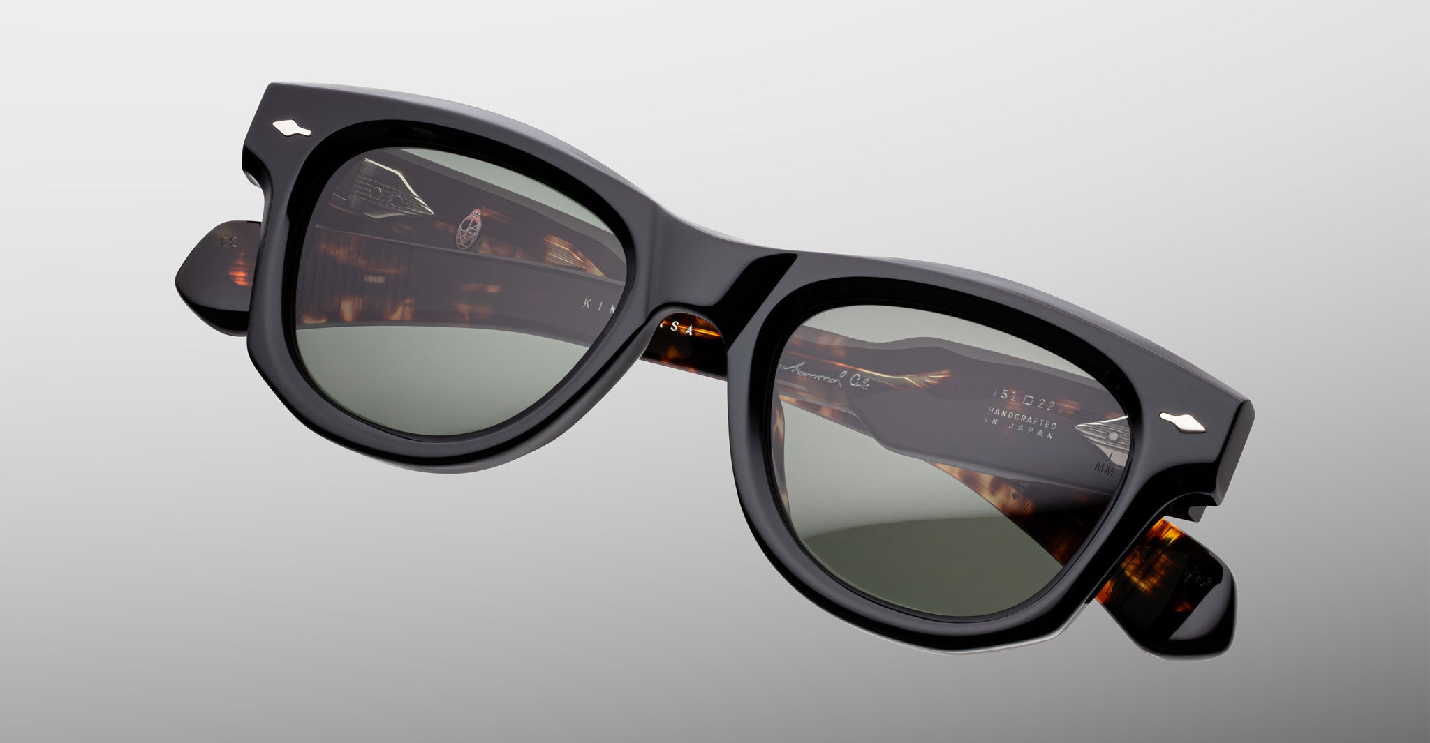 Jacques Marie Mage Kinshasa sunglasses, front view: black frames, green lenses, tortoiseshell-patterned inner arms.
