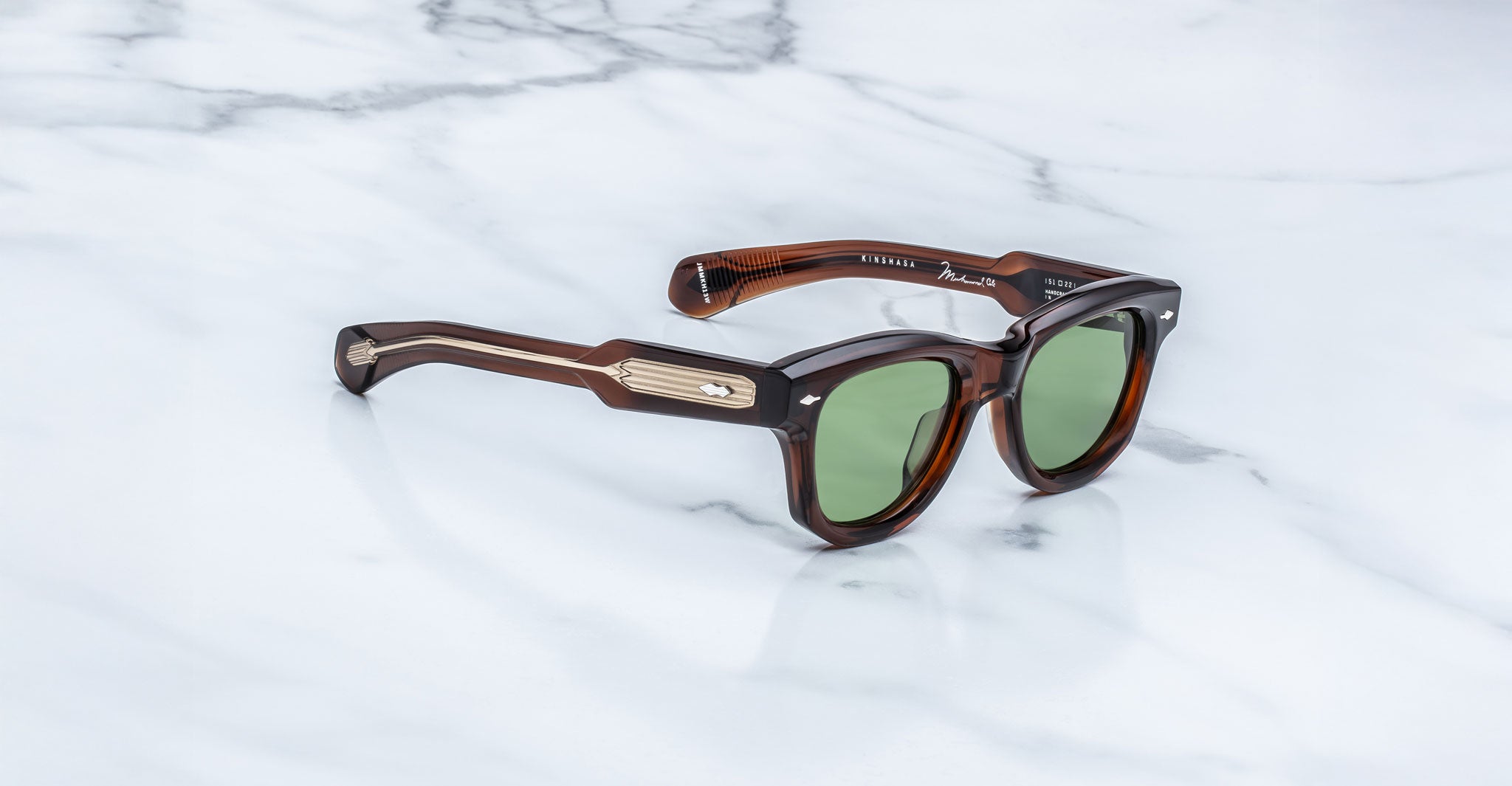 Jacques Marie Mage Kinshasa sunglasses with green polarized lenses and gold accents, shown from the front.