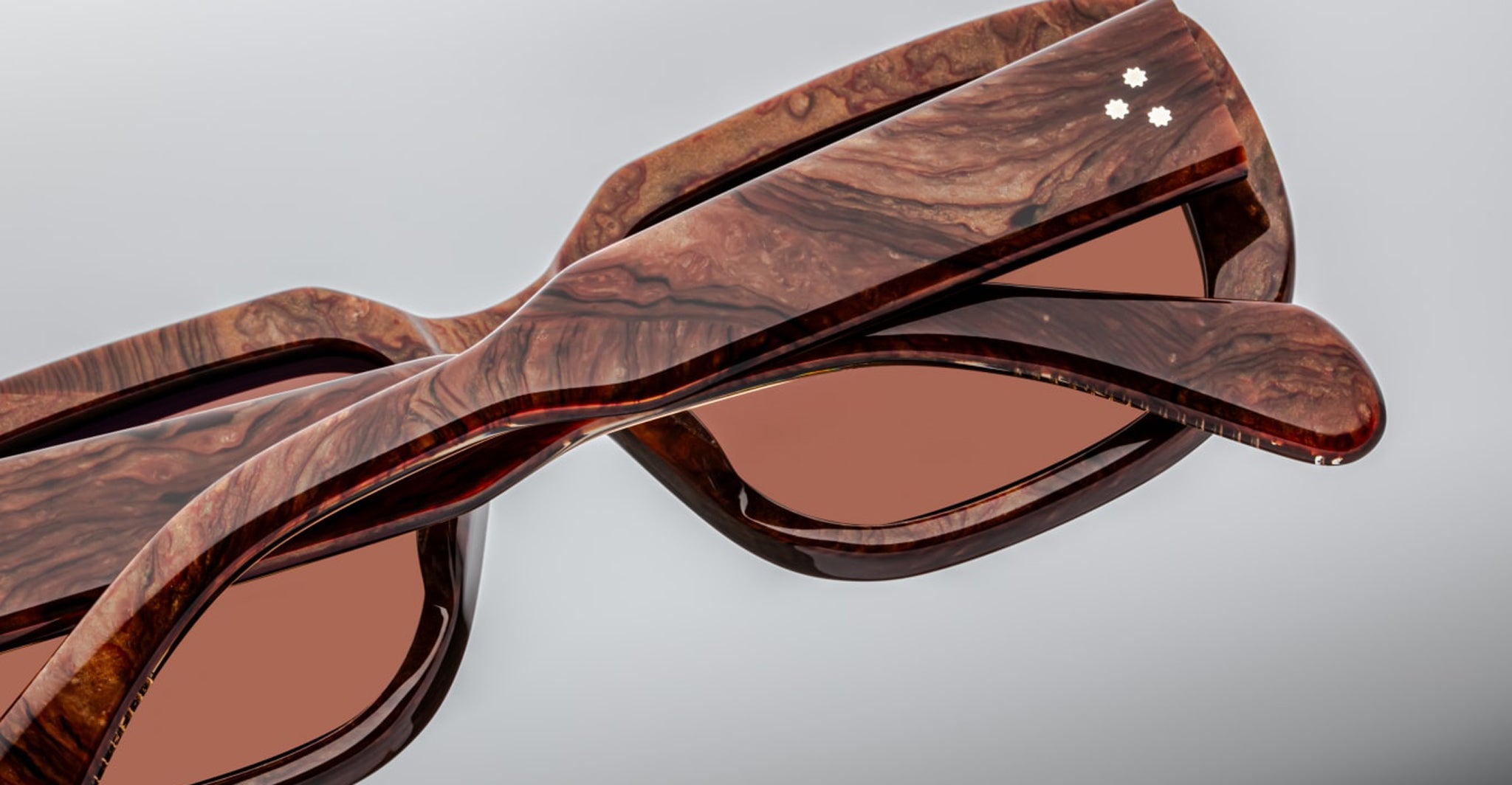 Close-up of Jacques Marie Mage Kobo sunglasses showing brown marbled frame and pink-tinted lenses, front angle view.