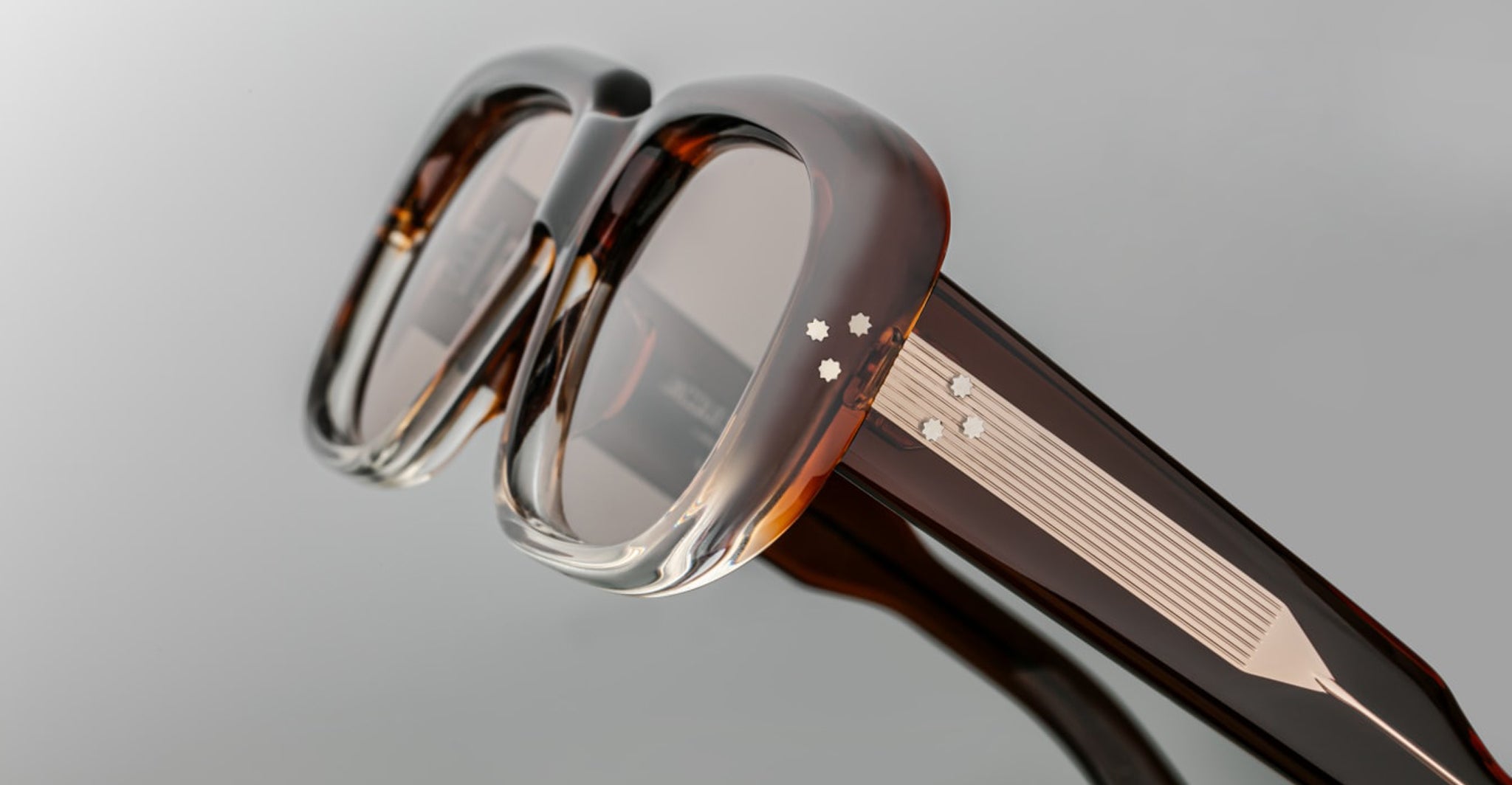 Close-up of Jacques Marie Mage Kobo eyeglasses, brown translucent frames, silver accents, and three-star detail at the temple.