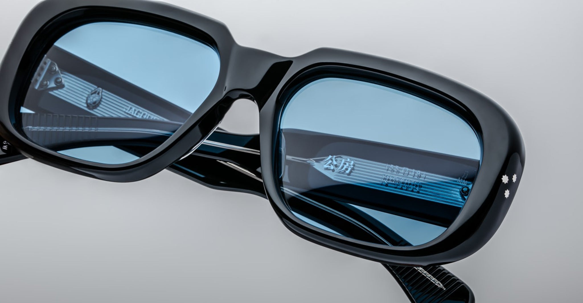 Close-up of Jacques Marie Mage Kobo black rectangular eyeglasses featuring blue-tinted lenses and silver temples.