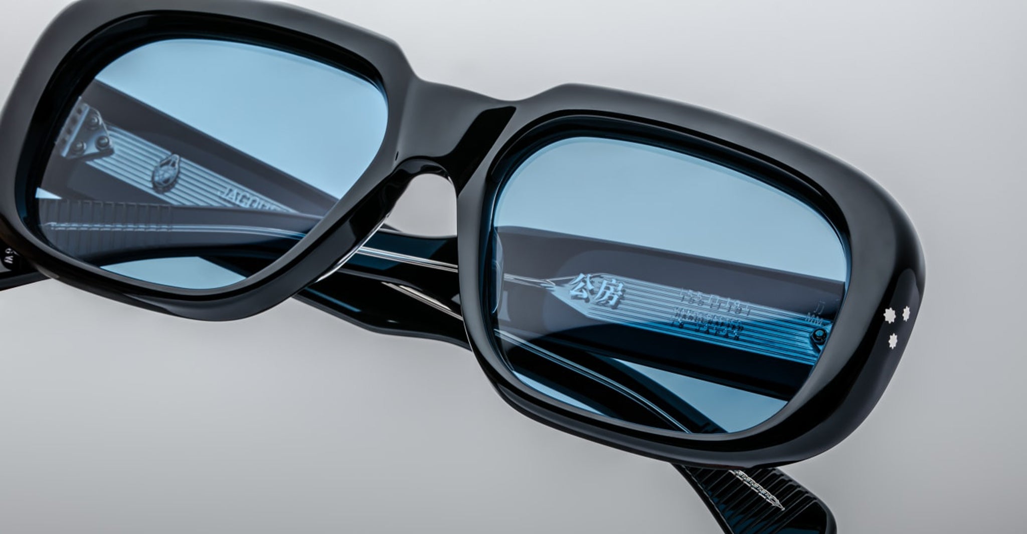 Close-up of Jacques Marie Mage Kobo black rectangular eyeglasses featuring blue-tinted lenses and silver temples.