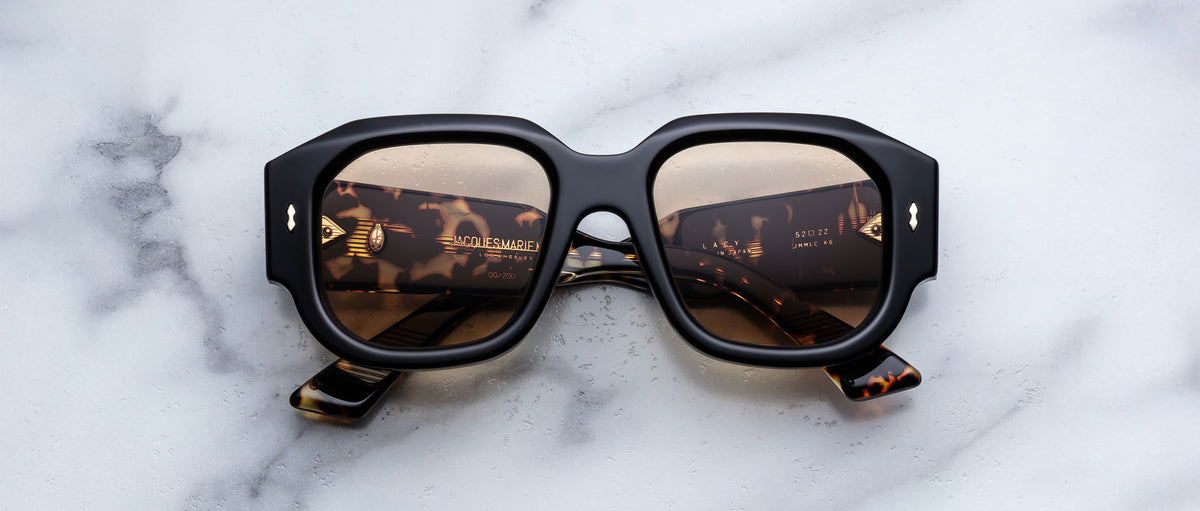 Jacques Marie Mage Lacy square tortoiseshell sunglasses with gold logo, top view showing the frames and branding detail.