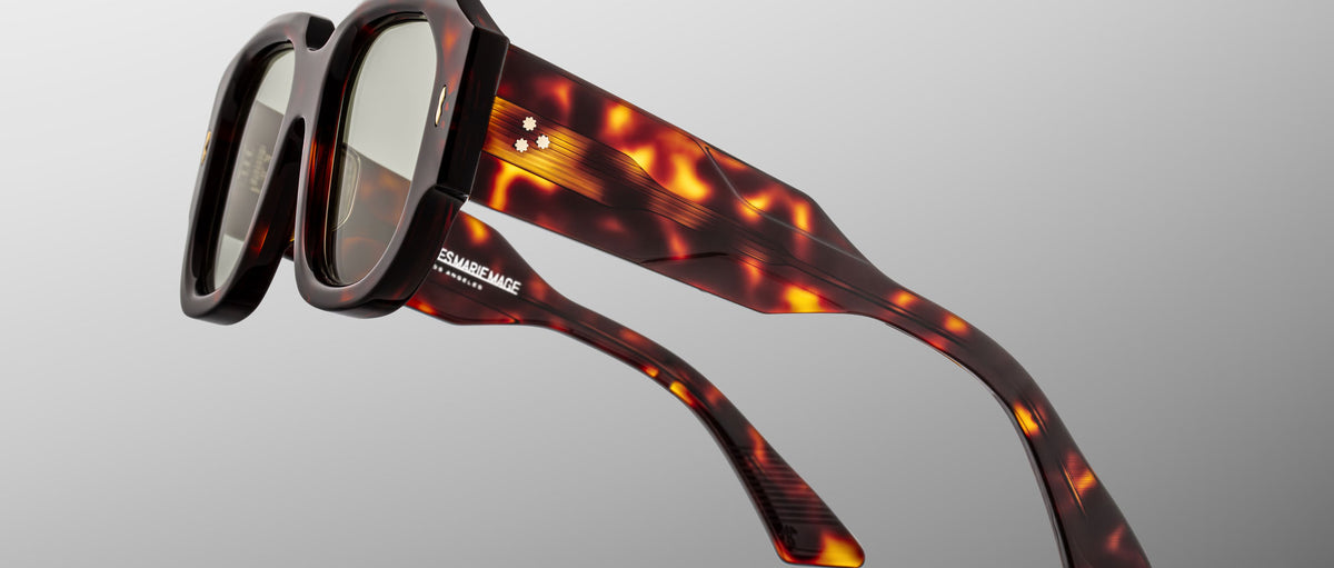 Jacques Marie Mage Lacy sunglasses, shown from a front angle, have thick brown tortoiseshell square frames and branded temples.