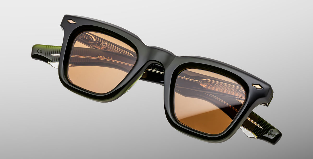 The Jacques Marie Mage Leclair sunglasses feature square-shaped frames in thick dark green and black acetate with brown-tinted lenses, displayed against a light gray background.