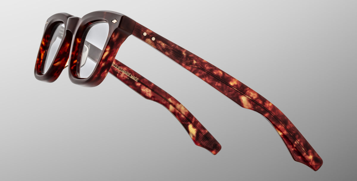 The Jacques Marie Mage Leclair glasses feature a thick, rectangular silhouette in glossy tortoiseshell acetate, showcased from a side angle against a plain light gray background.