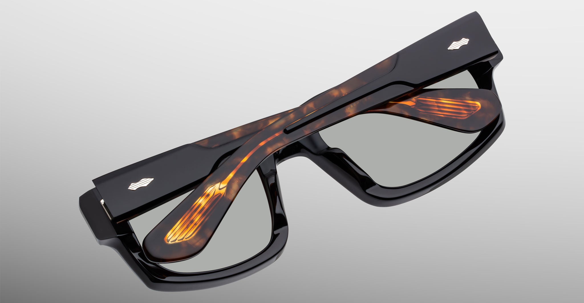 Jacques Marie Mage Louisville eyeglasses in black and tortoiseshell, folded with crossed temples, top-down view.
