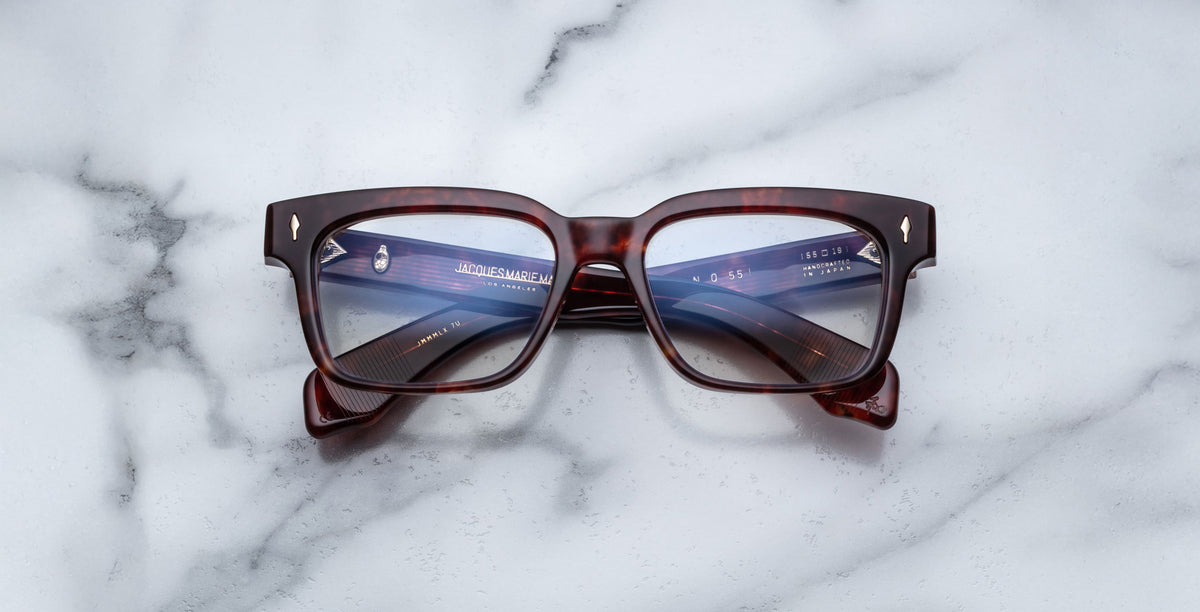 Jacques Marie Mage Molino 55 eyeglasses, front view, reflecting a digital screen on a white marble table.