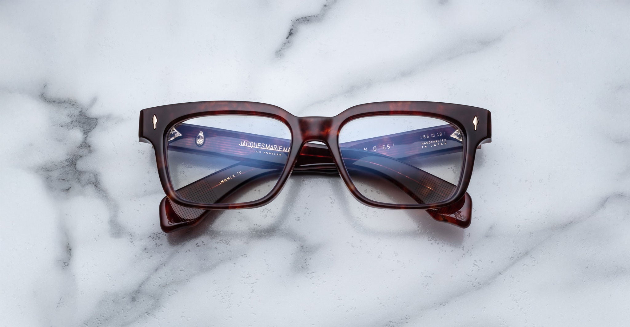 Jacques Marie Mage Molino 55 eyeglasses, front view, reflecting a digital screen on a white marble table.