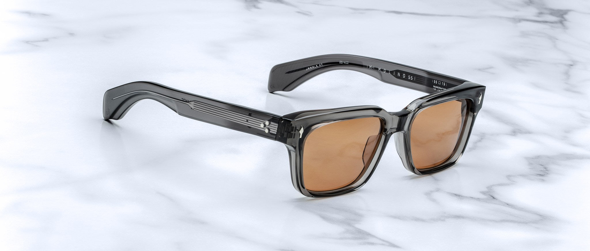 Jacques Marie Mage Molino 55 sunglasses, shown from the front, feature translucent gray square frames and UV-protection brown lenses.