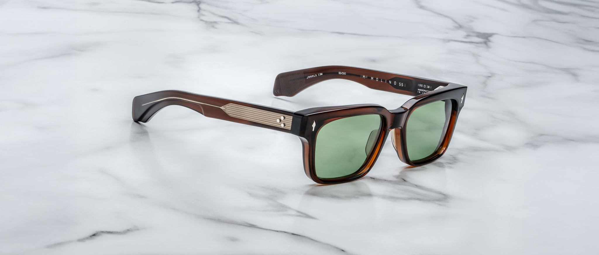 Jacques Marie Mage Molino 55 brown sunglasses with green lenses and metallic temple accents, shown from a top-down angle.