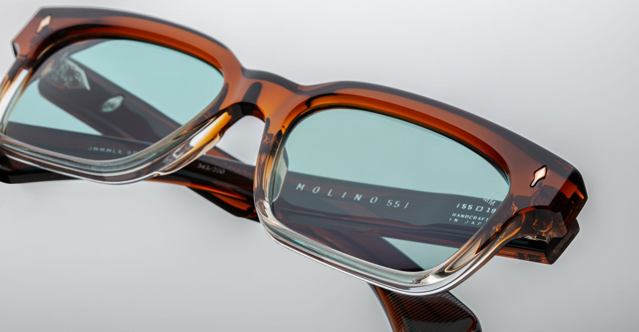 Jacques Marie Mage Molino brown rectangular eyeglasses shown close-up with light blue-tinted lenses, front view.