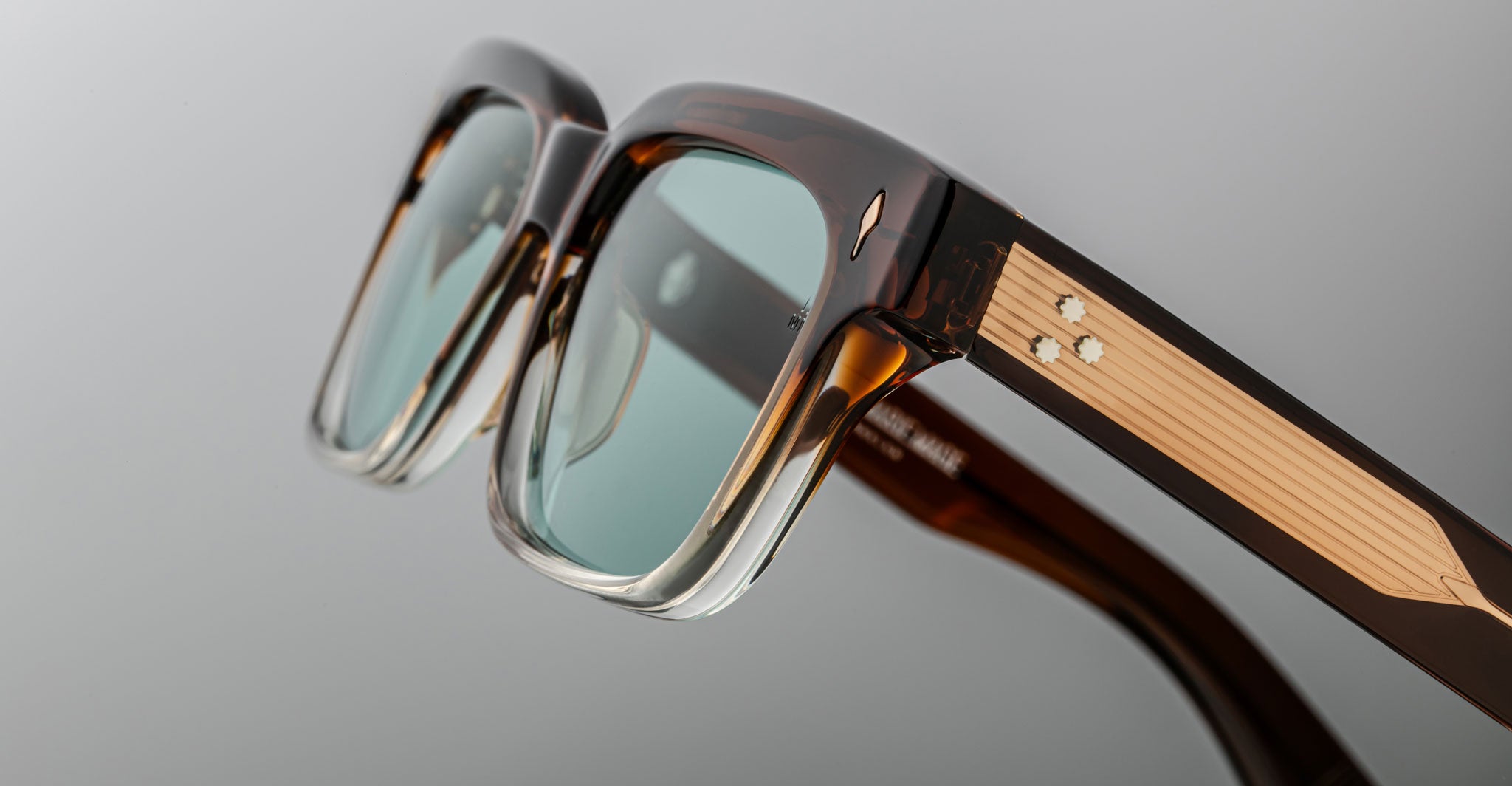 Close-up of Jacques Marie Mage Molino sunglasses with green-tinted lenses and metallic accents, viewed from the front.