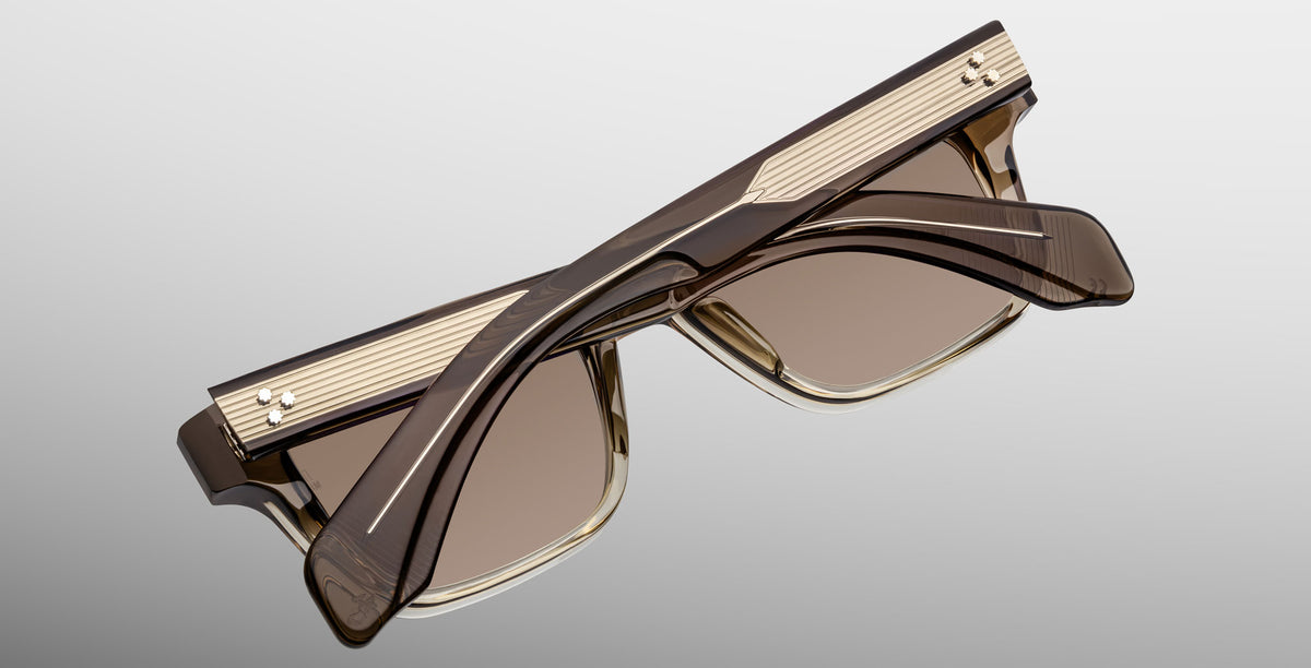 The Jacques Marie Mage Molino in Lescot are stylish, square-shaped brown sunglasses with gold accents and ribbed temple detailing, shown folded on a light gray background.