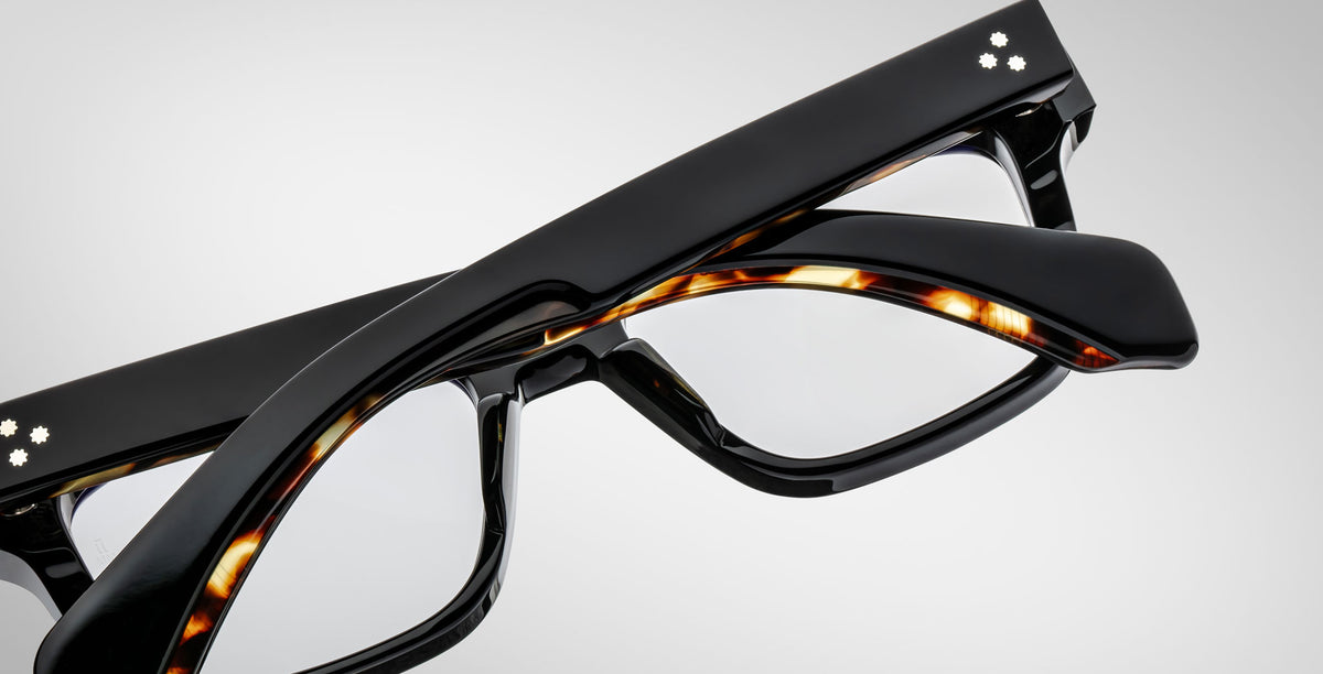 A pair of Jacques Marie Mage Molino in Noir 11, black and tortoise shell optical frame with clear lenses and silver decorative dots on the temples.