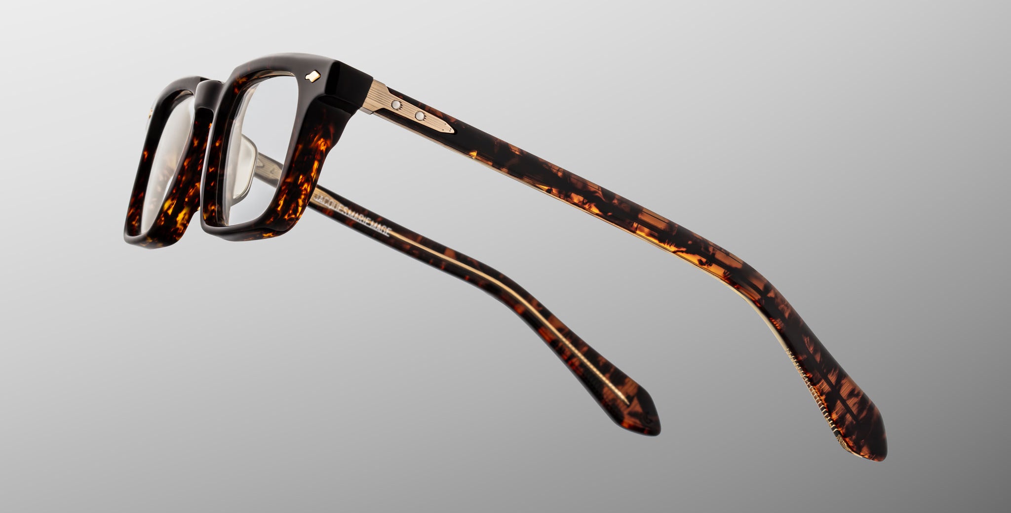 Jacques Marie Mage Moscova in Beau acetate optical frame, side profile highlighting sculpted tortoiseshell acetate, gold hardware at the hinge, signature arrowhead pin, and tapered temples with exposed core wire and warm tonal interior detailing