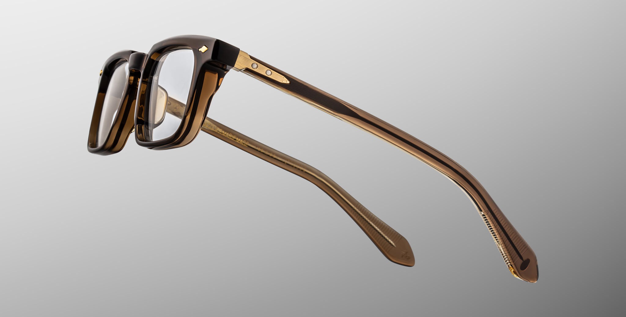 Jacques Marie Mage Moscova in London acetate optical frame, side profile highlighting sculpted translucent brown acetate, gold hardware at the hinge, signature arrowhead pin, and tapered temples with exposed core wire and warm tonal interior detailing