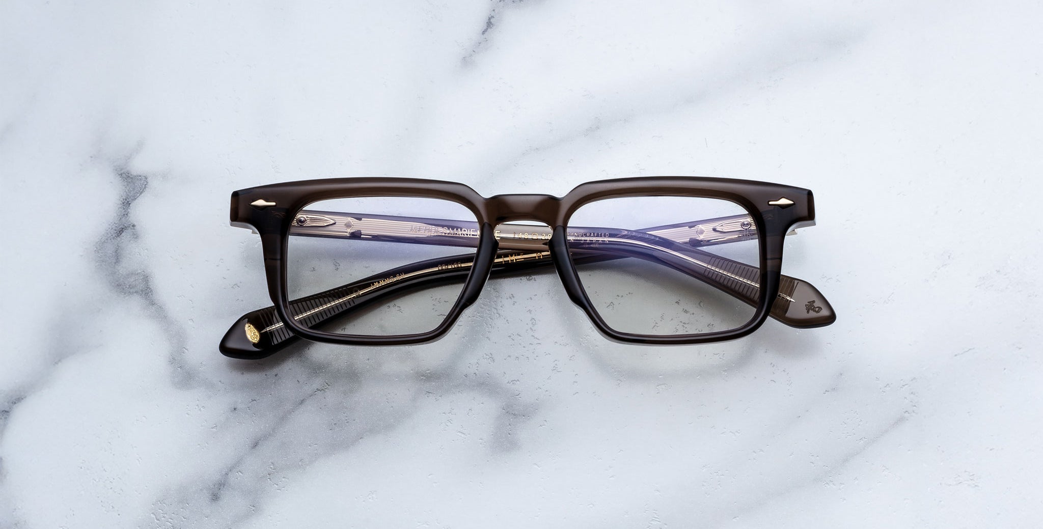 Jacques Marie Mage Moscova in London acetate optical frame, front-facing view with rectangular lenses, translucent brown acetate, signature arrowhead pins, and visible core wire temples with tonal interior detailing