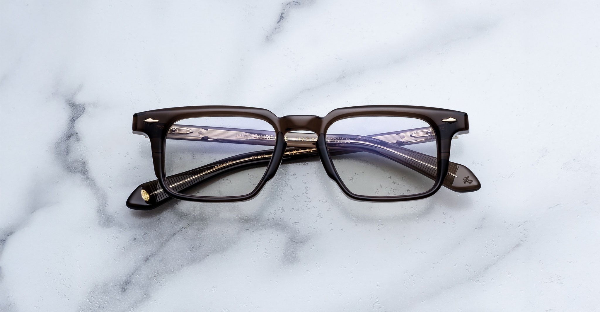 Jacques Marie Mage Moscova in London acetate optical frame, front-facing view with rectangular lenses, translucent brown acetate, signature arrowhead pins, and visible core wire temples with tonal interior detailing