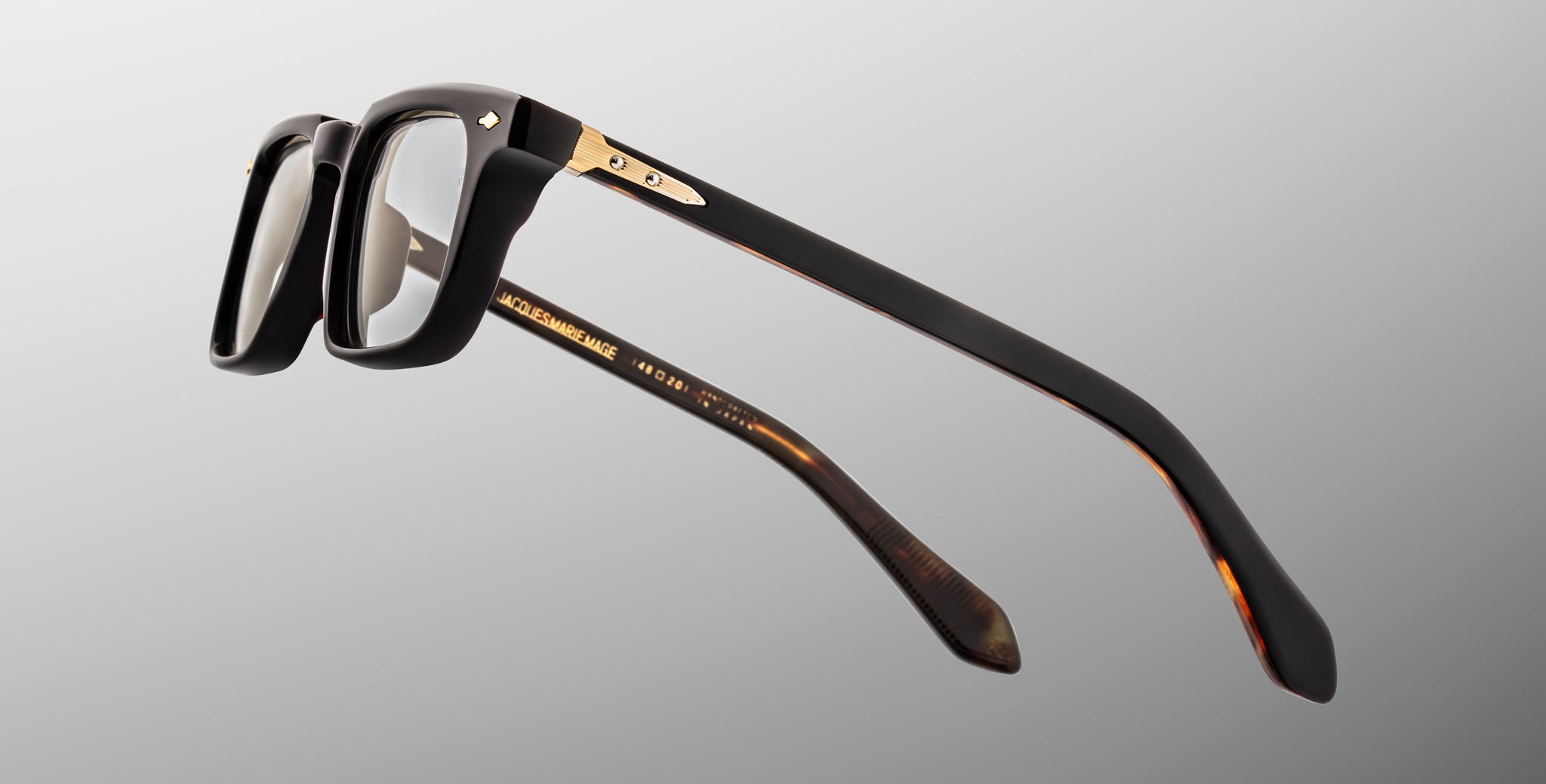 Jacques Marie Mage Moscova in Noir 15 acetate optical frame, side profile highlighting thick sculpted black acetate, gold hardware at the hinge, signature arrowhead pin, and tapered temples with exposed core wire and tortoiseshell interior detailing