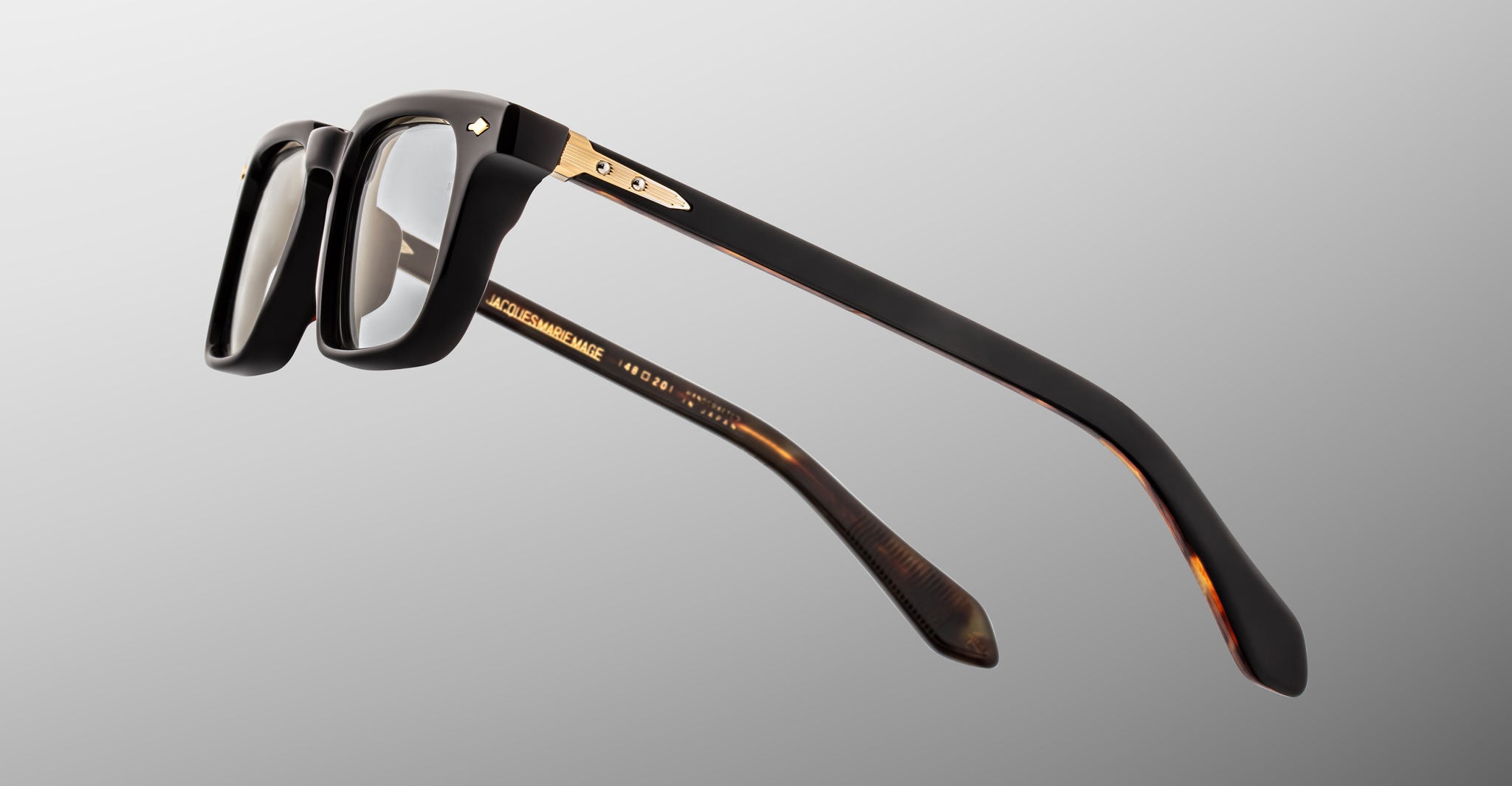 Jacques Marie Mage Moscova in Noir 15 acetate optical frame, side profile highlighting thick sculpted black acetate, gold hardware at the hinge, signature arrowhead pin, and tapered temples with exposed core wire and tortoiseshell interior detailing